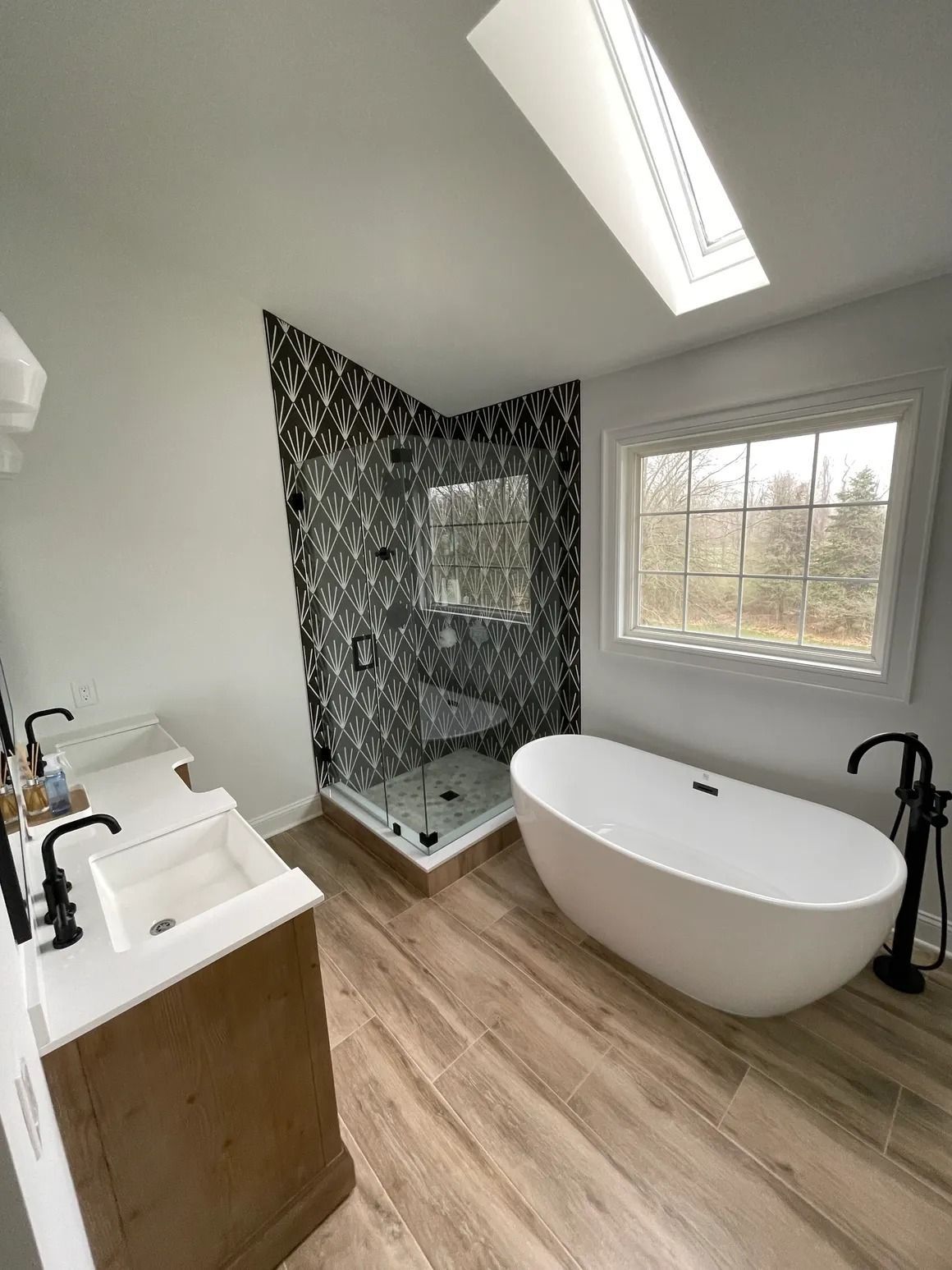 Modern bathroom with a patterned tile shower, freestanding tub, and double vanity.