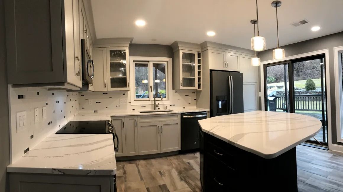 Modern kitchen with gray cabinets, quartz countertops, black appliances, and island.