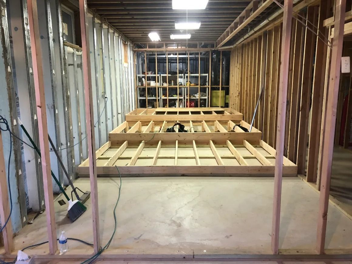 Basement under construction; wood framing and concrete floor; step-up platforms are built.