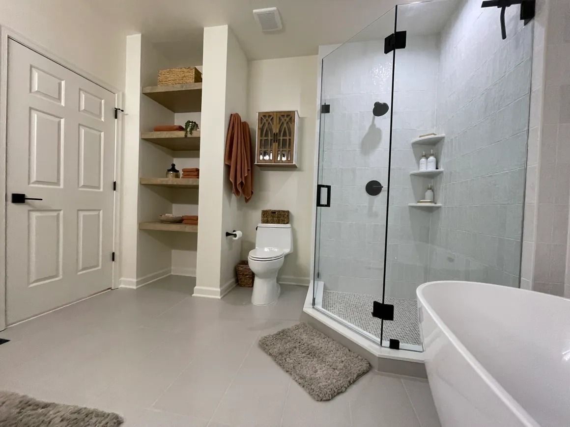 Modern bathroom with white walls, glass shower, and freestanding tub.
