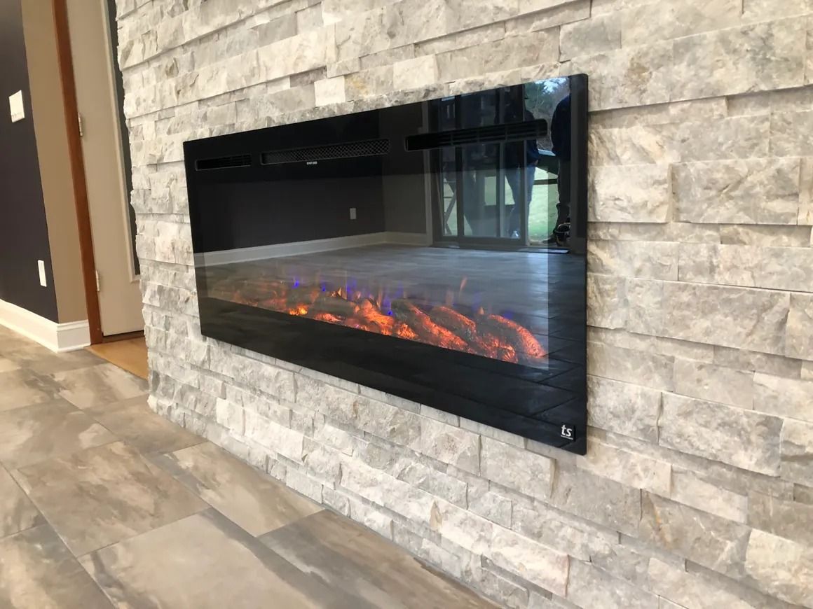 Electric fireplace mounted on a light-colored stone wall. The flames are orange and blue.
