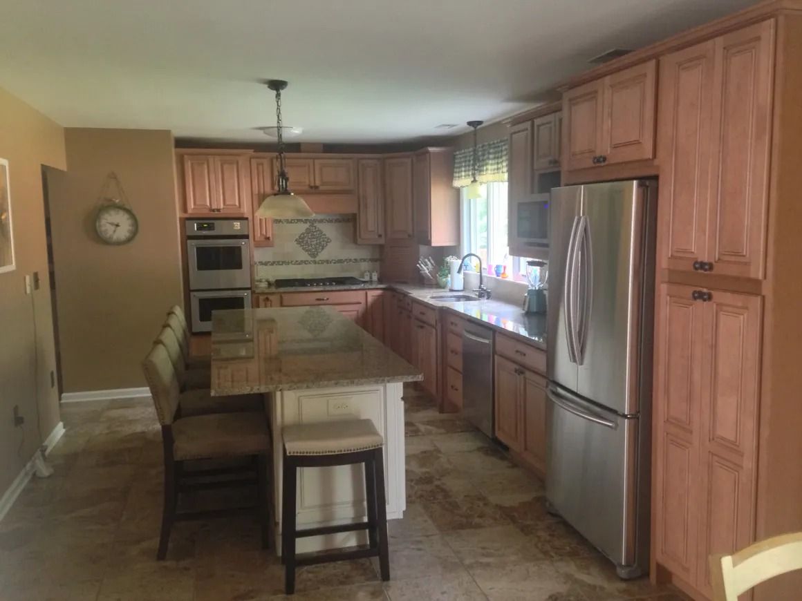 Kitchen with light brown cabinets, stainless steel appliances, and a granite countertop island.