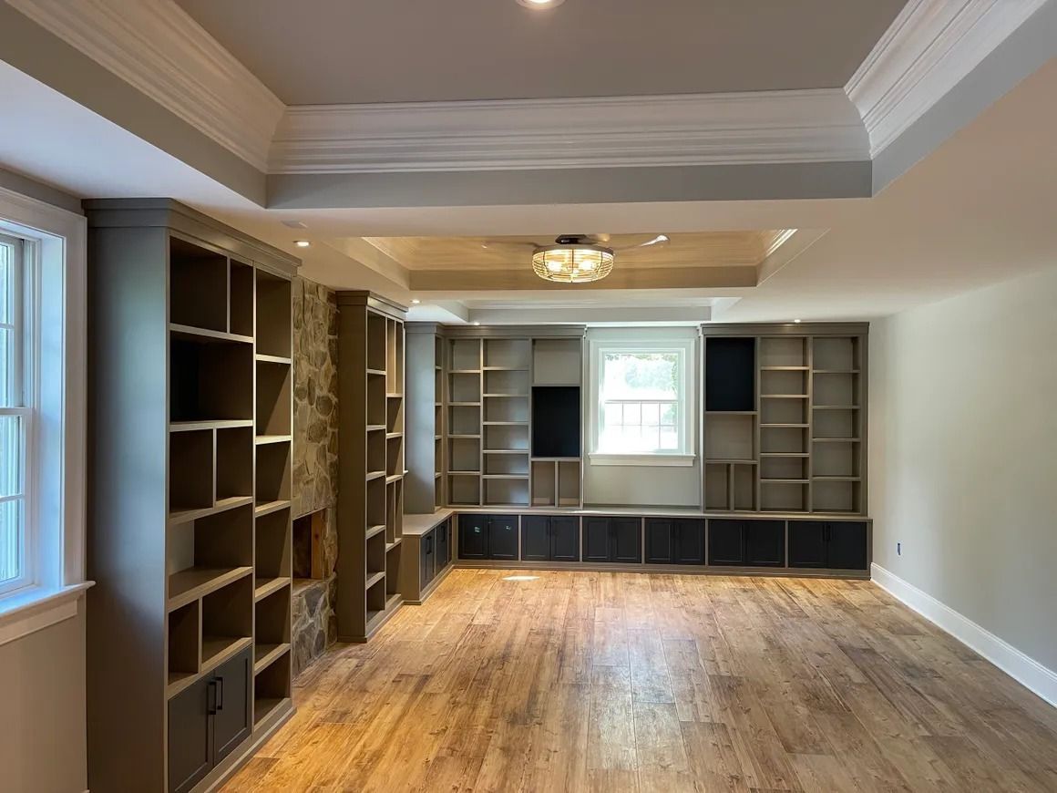 Empty room with built-in bookshelves, wooden floor, and decorative ceiling.