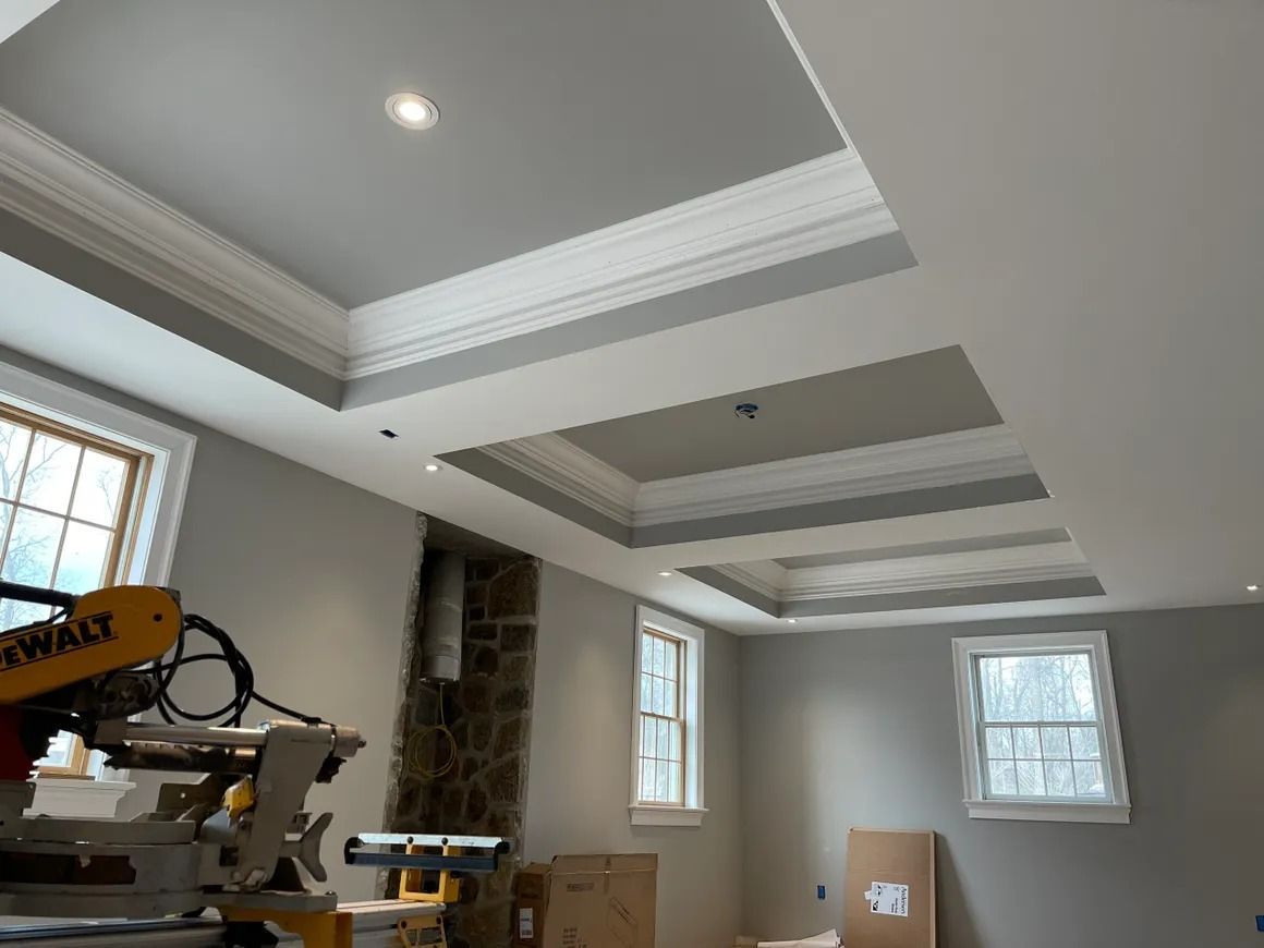 Room with recessed ceiling design, gray walls, white trim, and a miter saw in the corner.