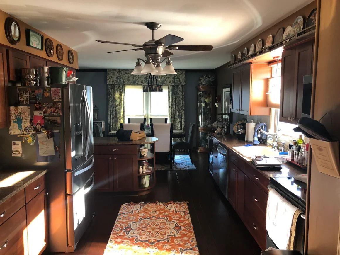 Kitchen with dark wood cabinets, stainless steel refrigerator, and a table with chairs in the background.
