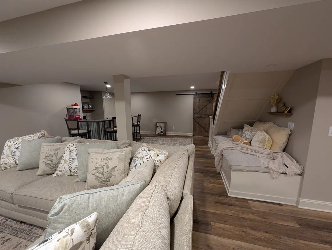 Cozy basement living area with a large sofa, built-in bed nook, and dining area.