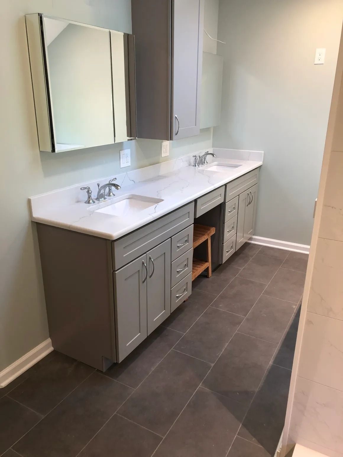 Bathroom with gray cabinets, white countertop, two sinks, and dark tiled floor.