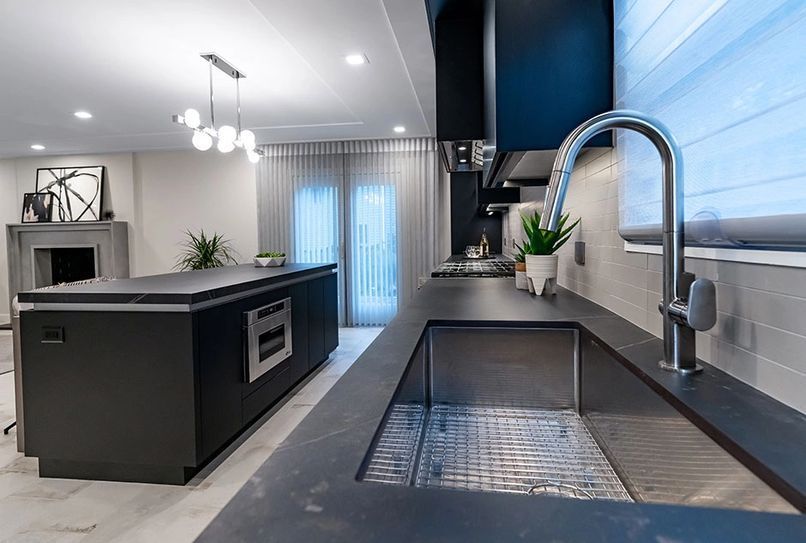 Modern kitchen with dark cabinetry, stainless steel sink and faucet.