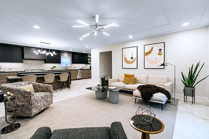 Modern living room and kitchen. Neutral colors, contemporary furniture, abstract art, and indoor plants.