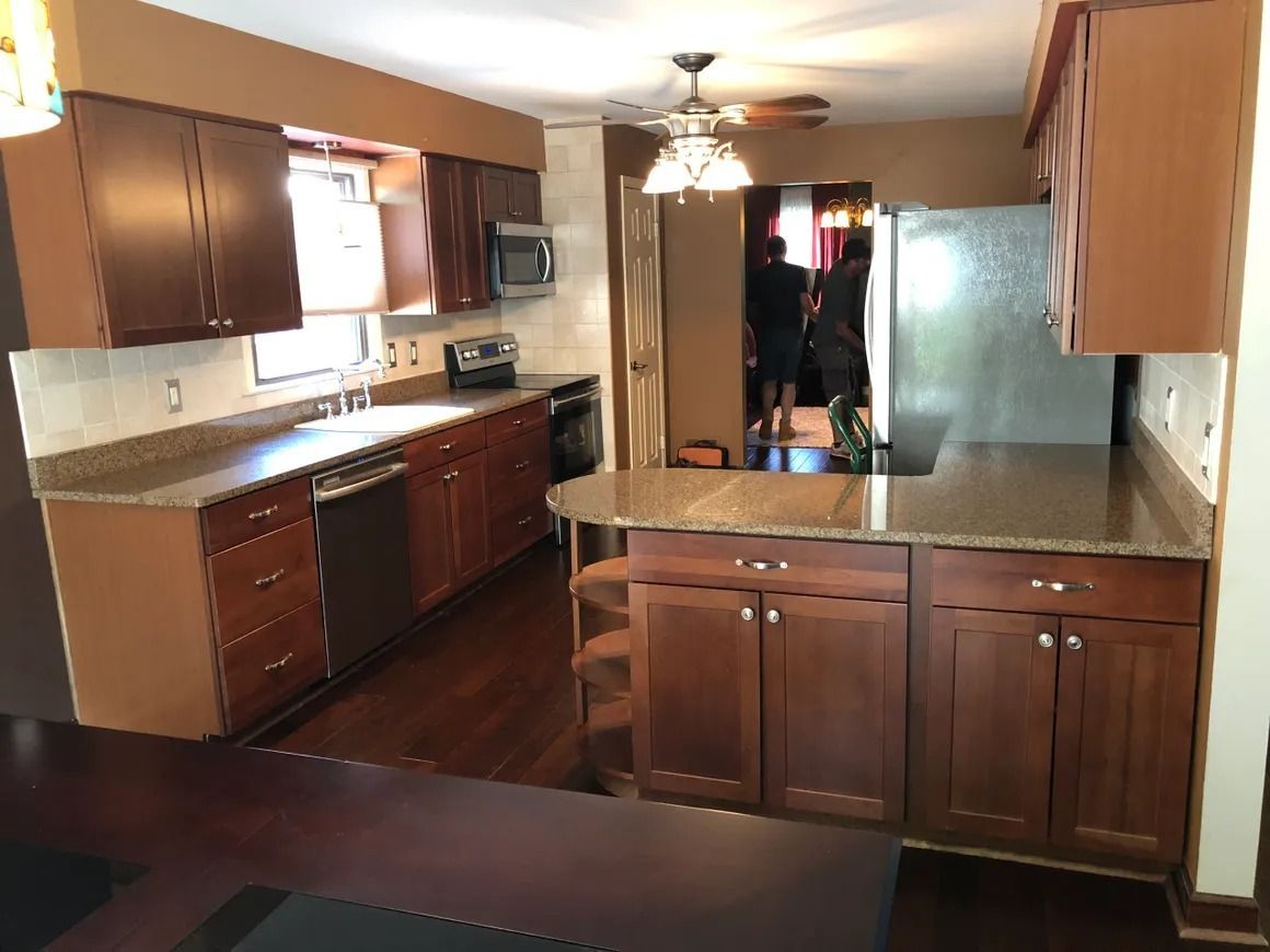 Kitchen with dark wood cabinets, granite countertops, stainless steel appliances, and hardwood floors.