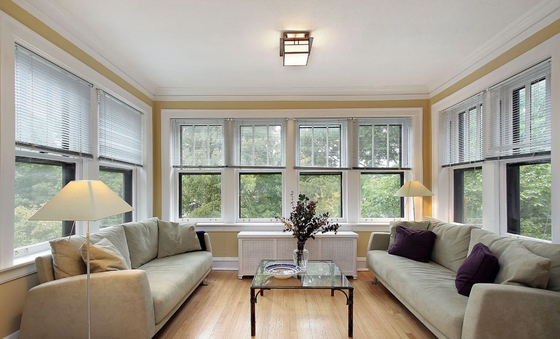A light green house with a white garage door, porch, and a blue sky.