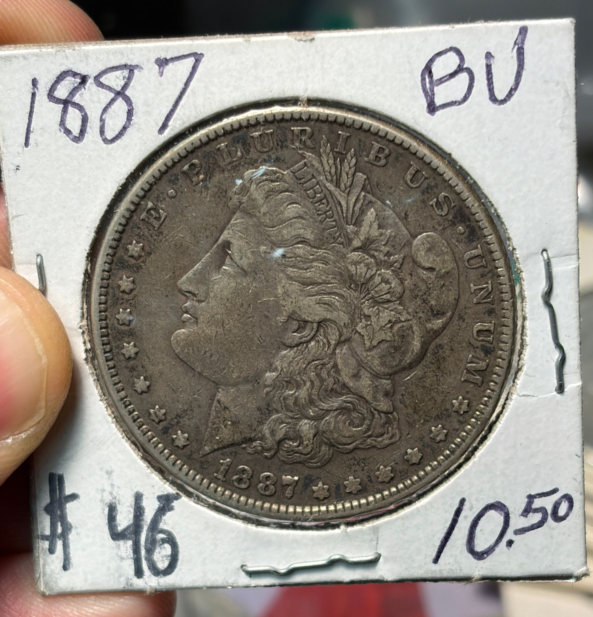 1887 Morgan silver dollar coin on a white card marked “BU,” price $46.50