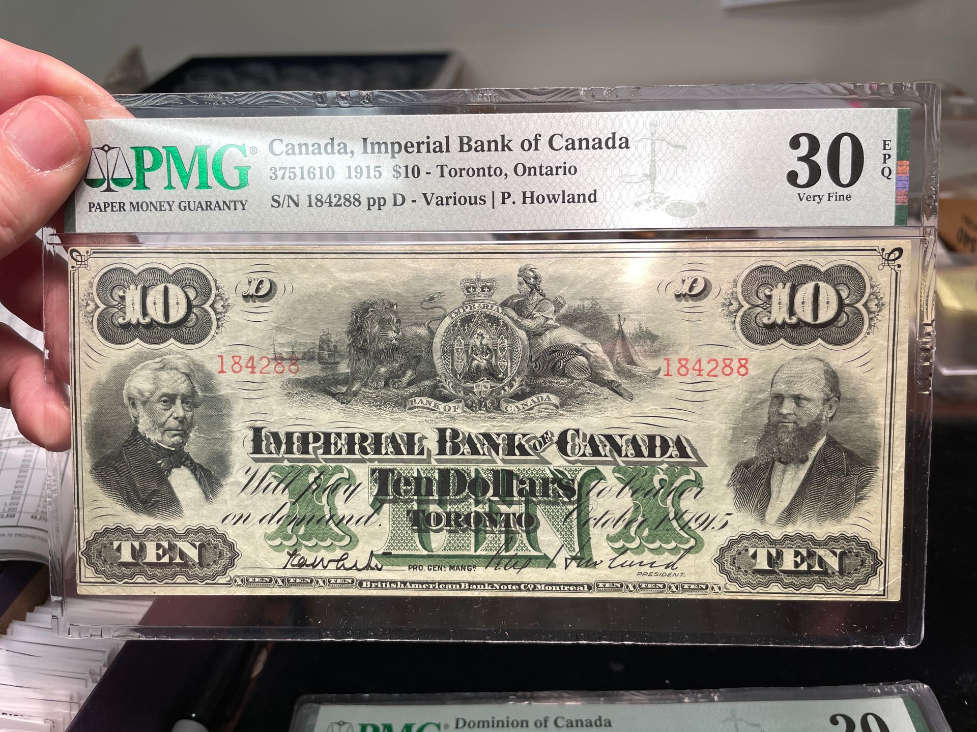 Hand holding a graded 1910 Canadian Bank of Commerce $10 bill in a protective case