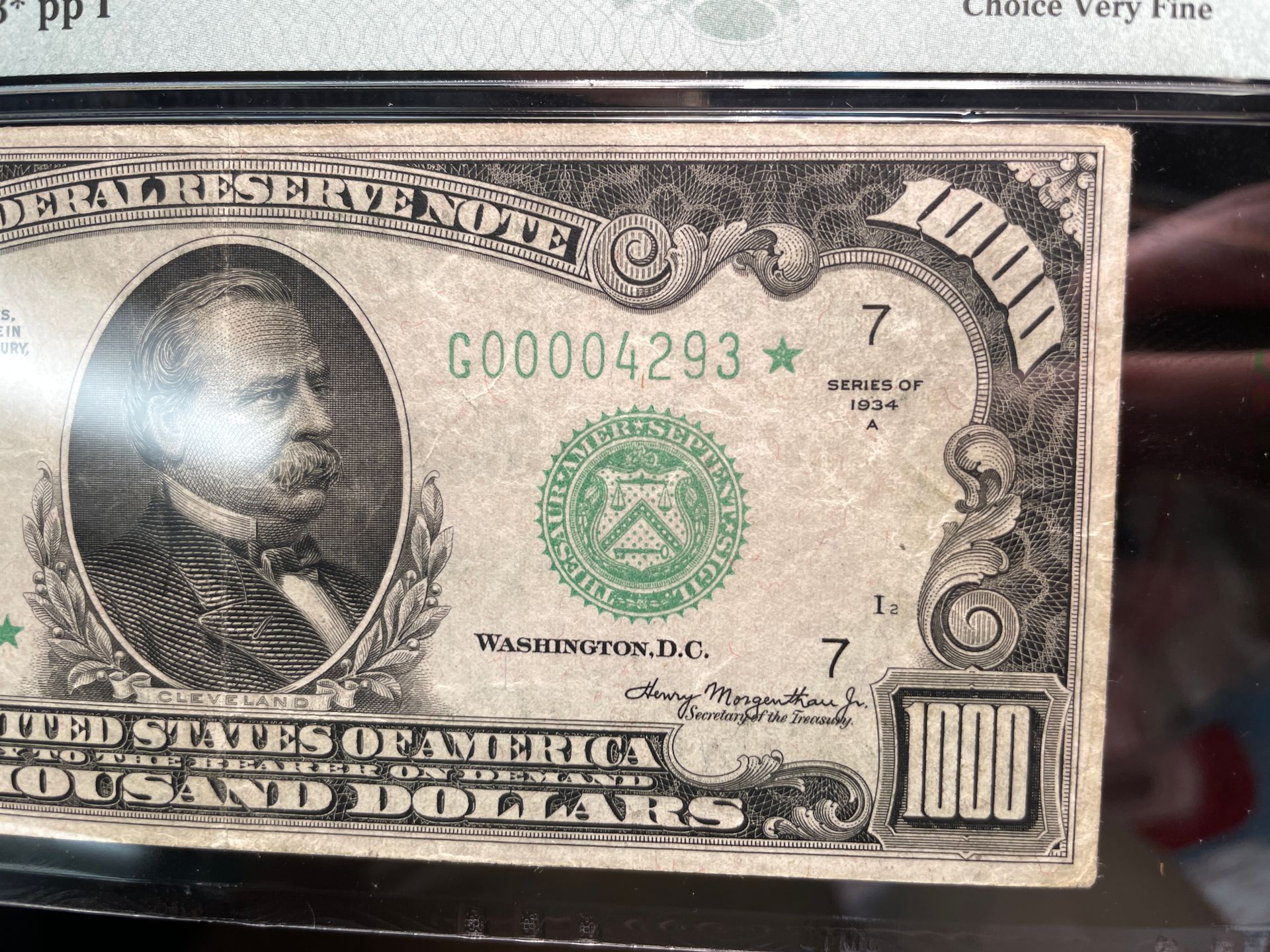Close-up of a worn U.S. $1 bill with visible green seal and serial number, photographed on a blue surface