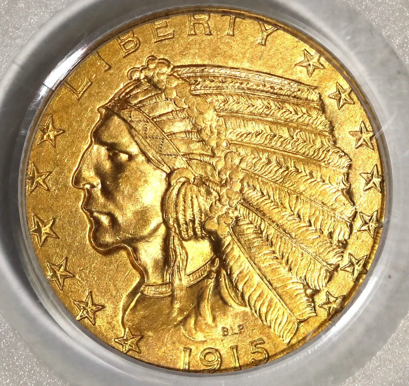 Gold Native American head coin in a clear plastic holder, showing the obverse with stars and 1913 at bottom