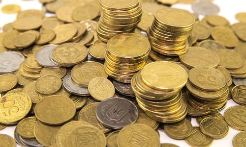 Pile of gold coins stacked and scattered on a white surface