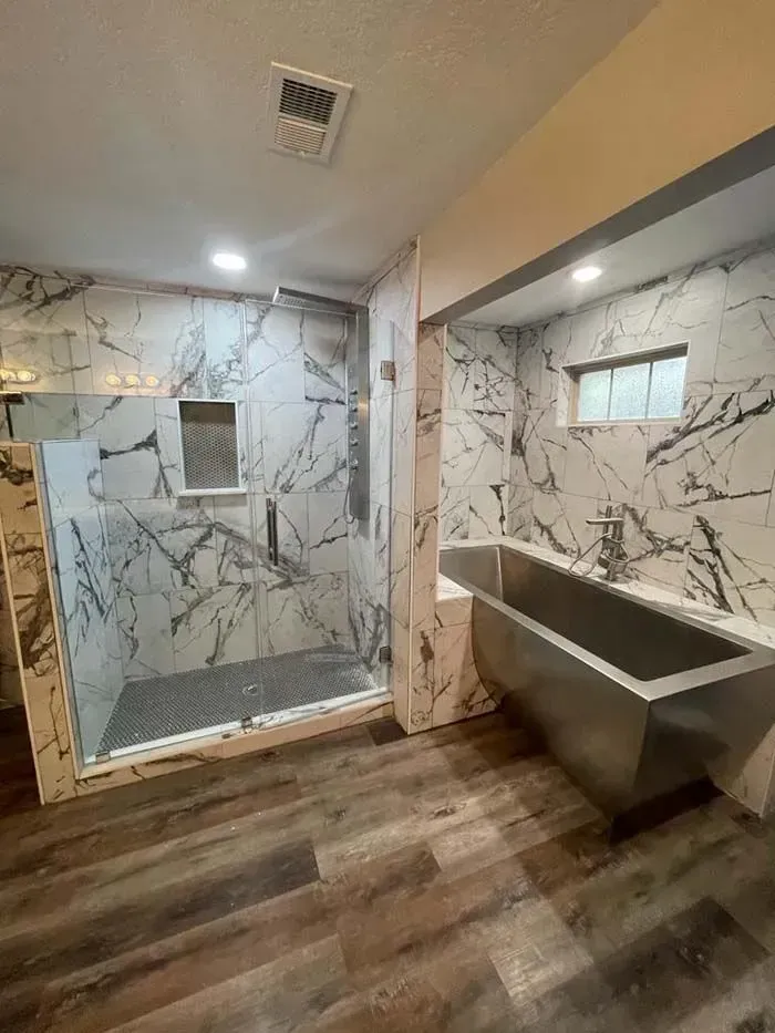 Modern bathroom with marble-pattern tile, walk-in shower, and a concrete sink vanity