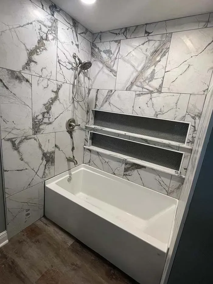Marble-tiled bathroom with a built-in rectangular tub and recessed wall shelves