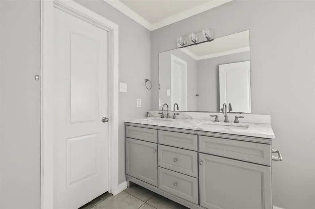 Bright bathroom with double vanity, large mirror, and white cabinets.