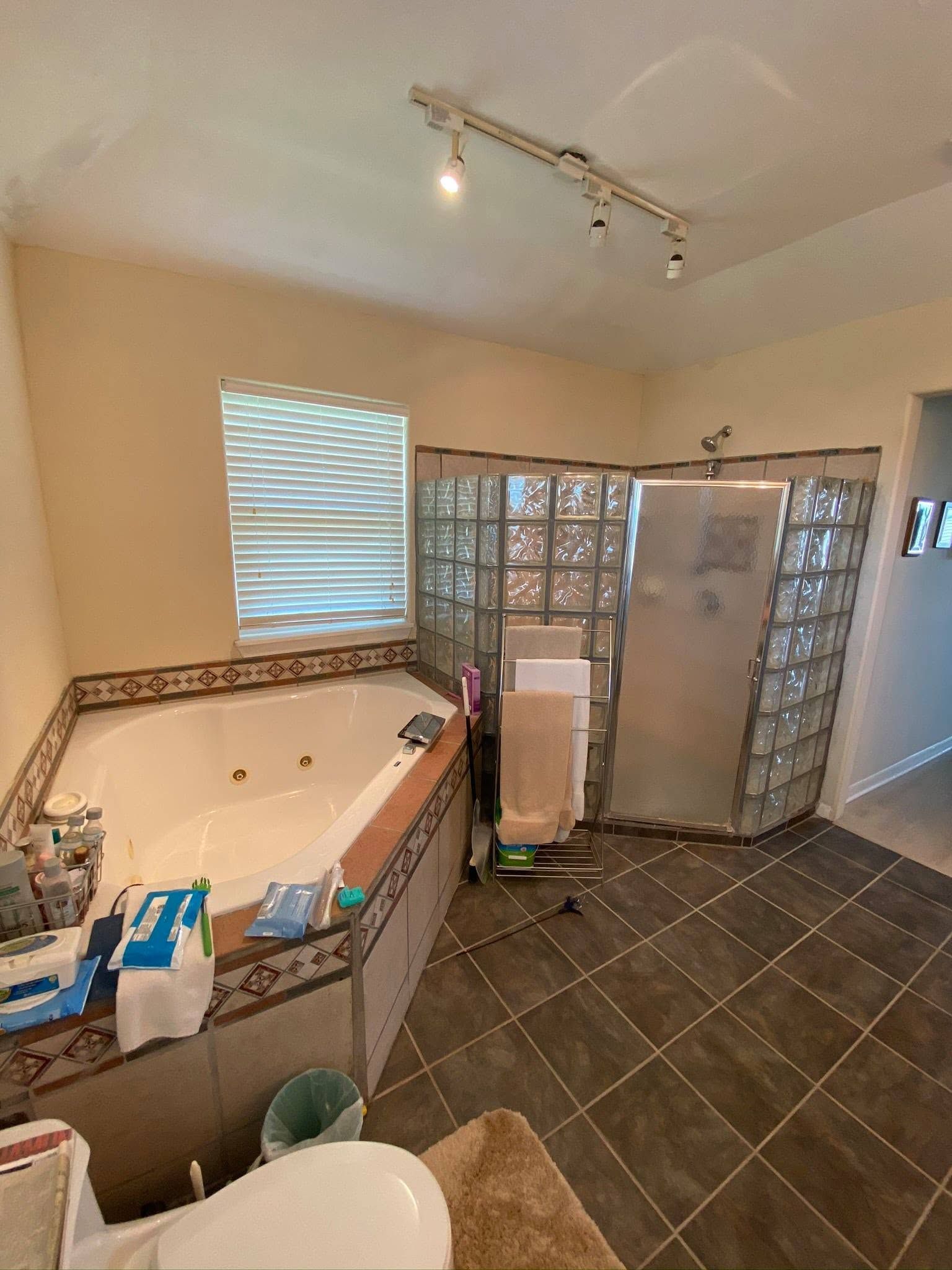 Bathroom under renovation with tiled floor, walk-in shower, vanity, and construction materials scattered around.