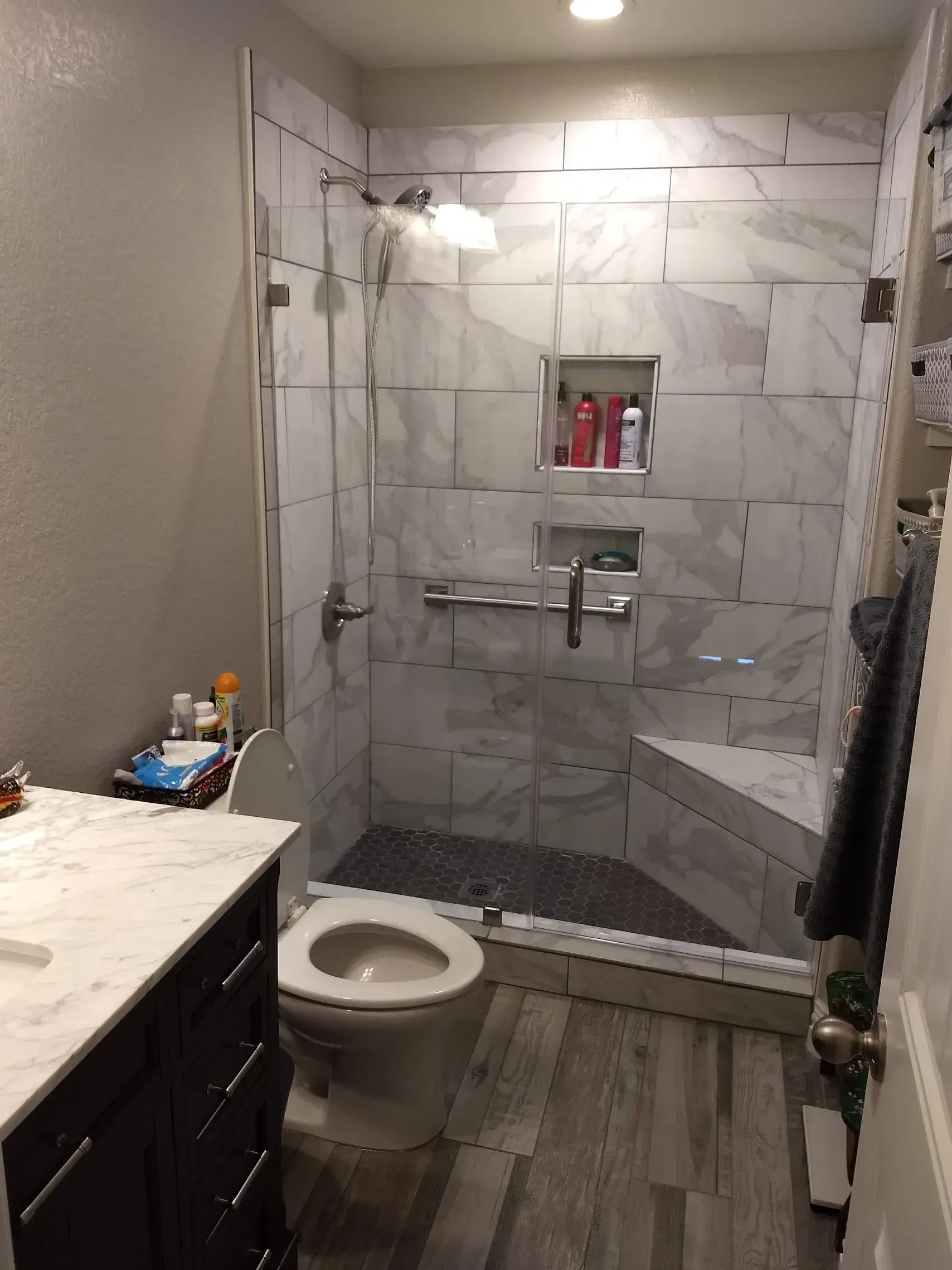 Small bathroom with marble-look shower, toilet, and vanity in gray tones