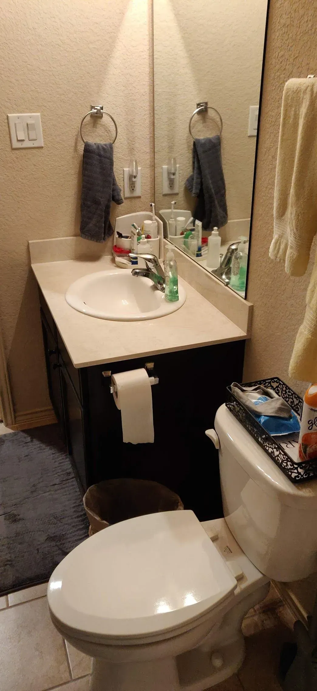 Small bathroom with toilet, vanity sink, mirror, and towel hanging beside a shower curtain.