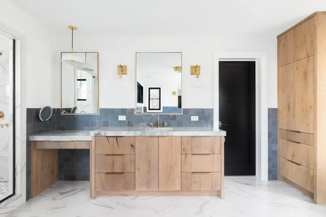 Modern bathroom with wood vanity, double mirrors, marble floor, and black door accents