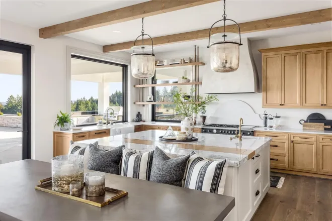 Bright modern kitchen with wood cabinets, island seating, pendant lights, and large windows
