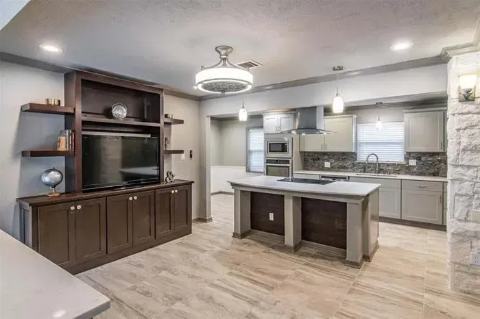 Modern kitchen and living area with island, dark wood cabinets, stainless appliances, and light floors