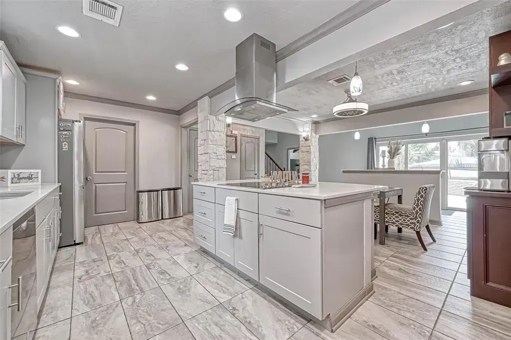 Bright modern kitchen with white cabinets, island, stainless hood, and light wood floors