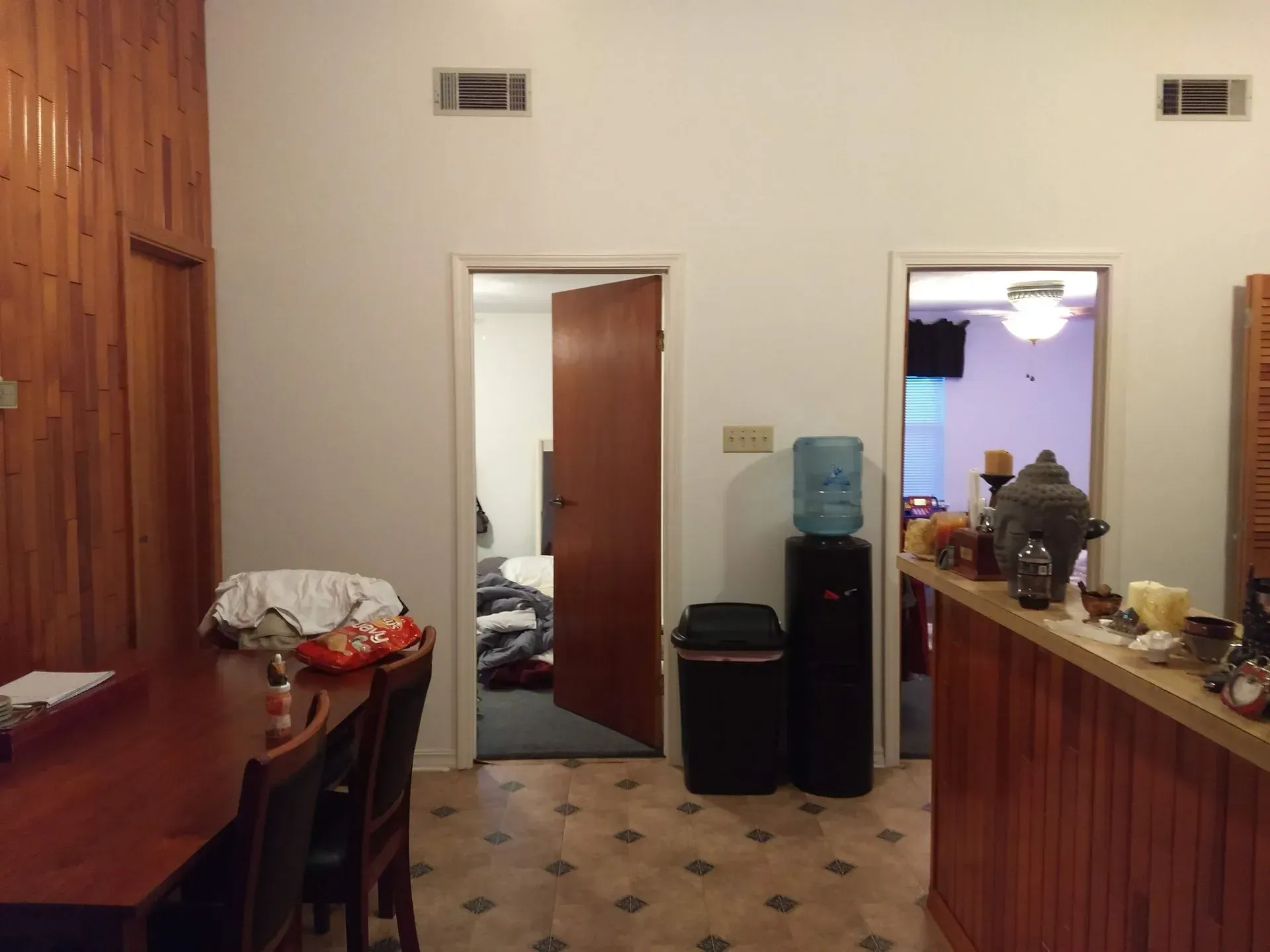 Empty room with wooden counter, open doorway, and water cooler in a tiled interior