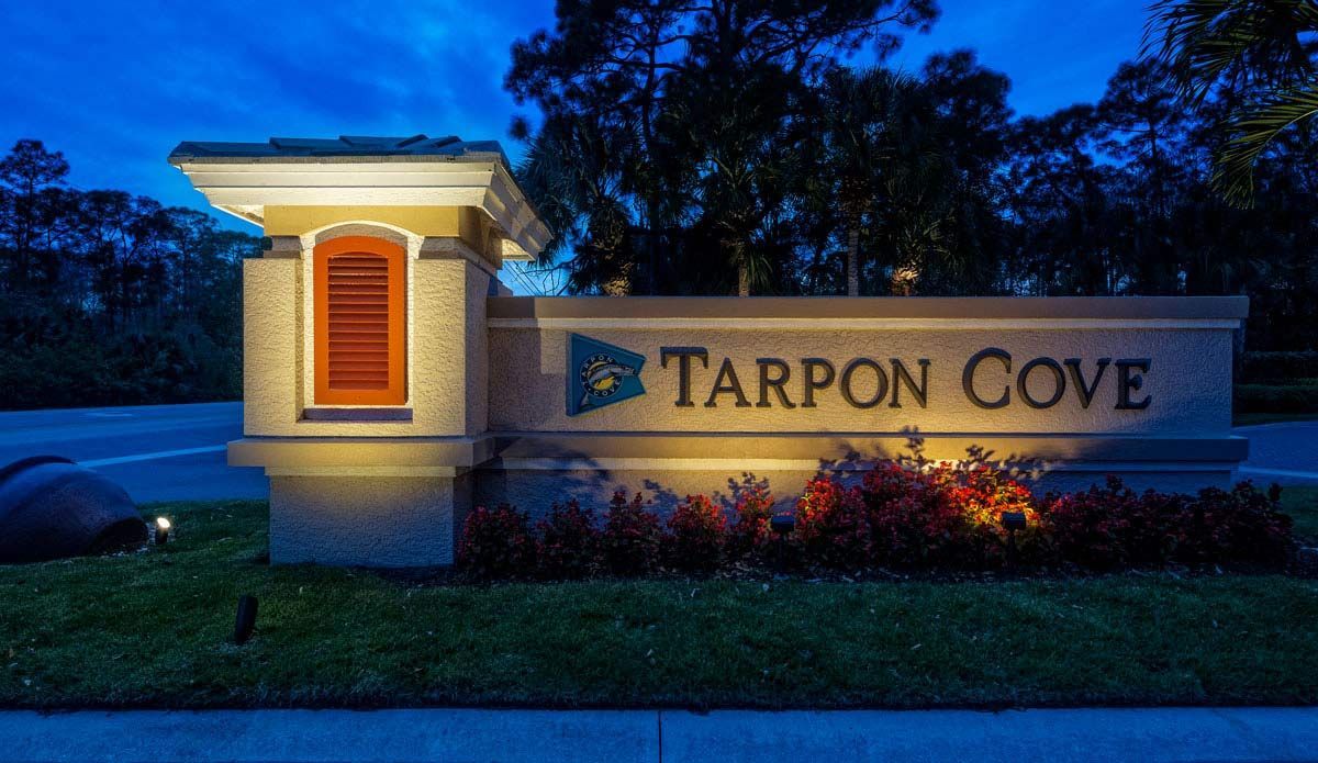 Entrance sign for Tarpon Cove, illuminated at dusk, with the name in large letters.