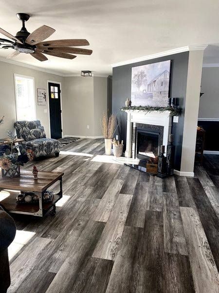Living room with gray wood-look flooring, fireplace, and a dark accent wall.