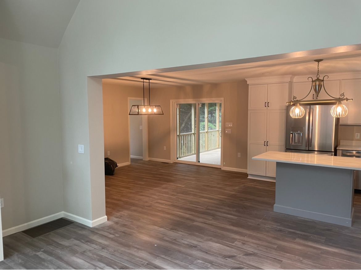 Open concept living space with kitchen island, wood flooring, and deck access.