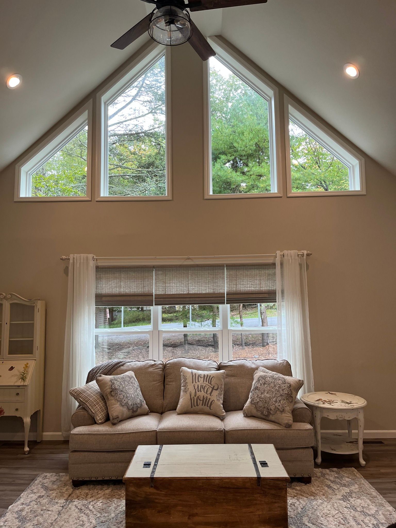 Living room with high ceilings, large windows, sofa, and coffee table.
