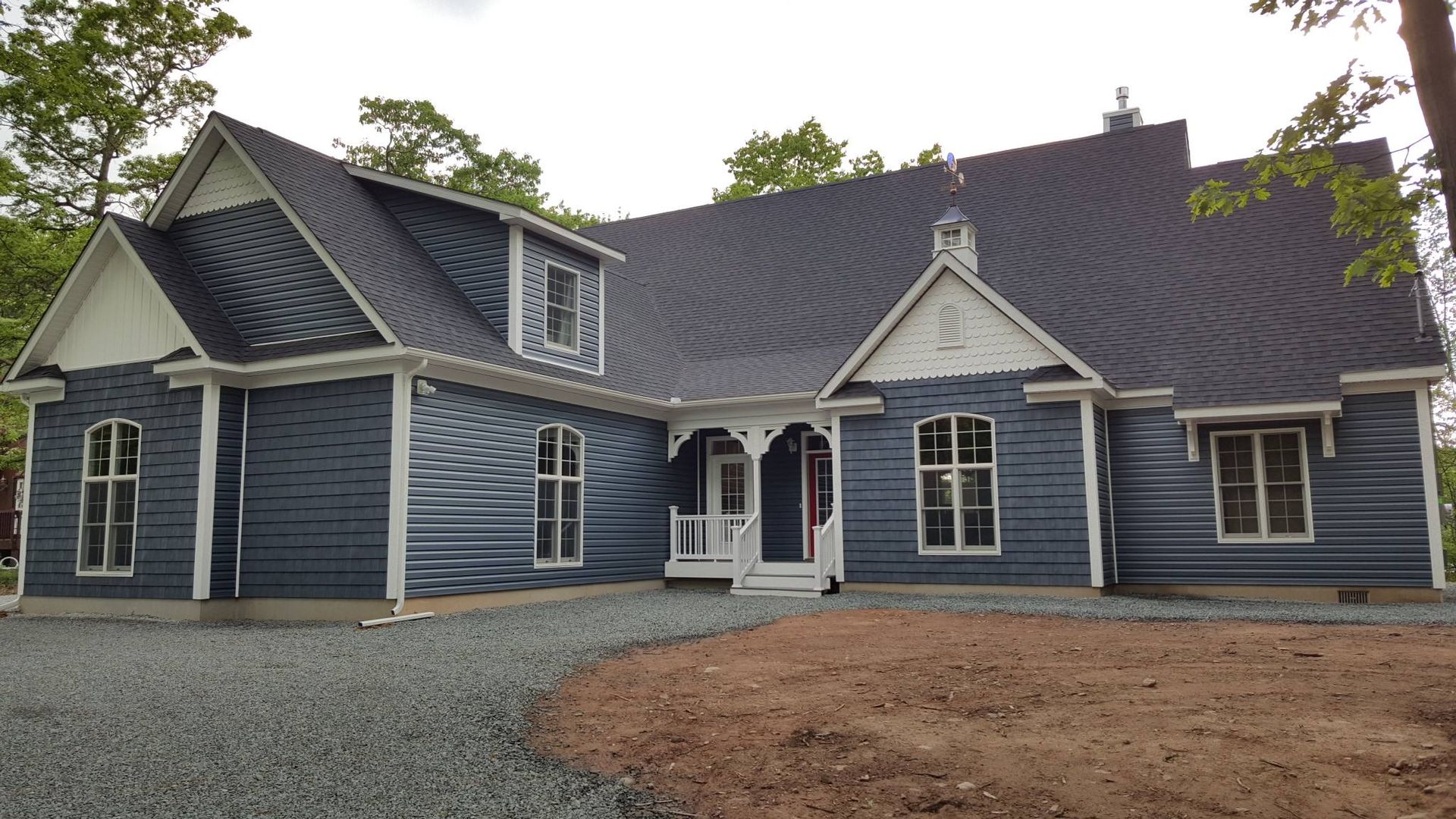 Blue house with white trim, gray gravel path, and dark roof.