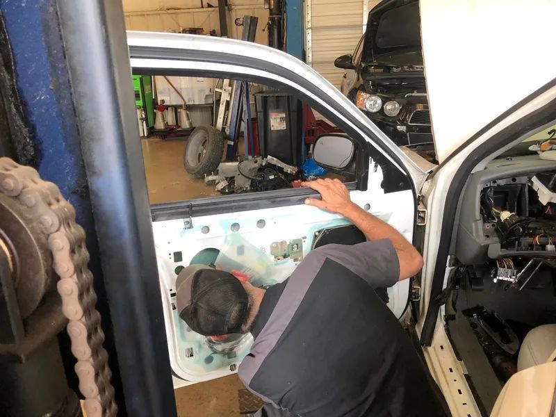 Mechanic working on a car door in a garage.