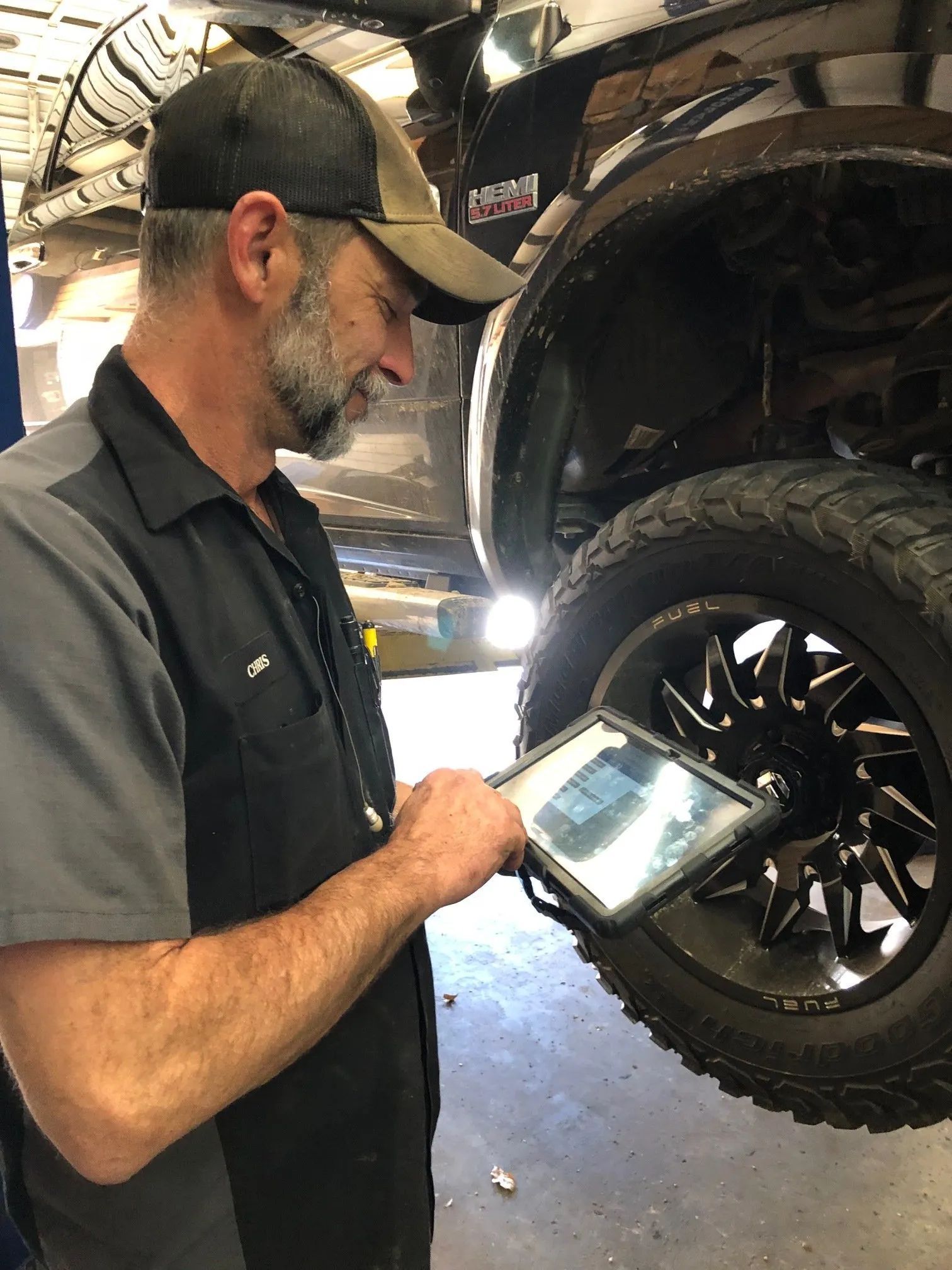 Mechanic examines tire with a tablet in a garage.