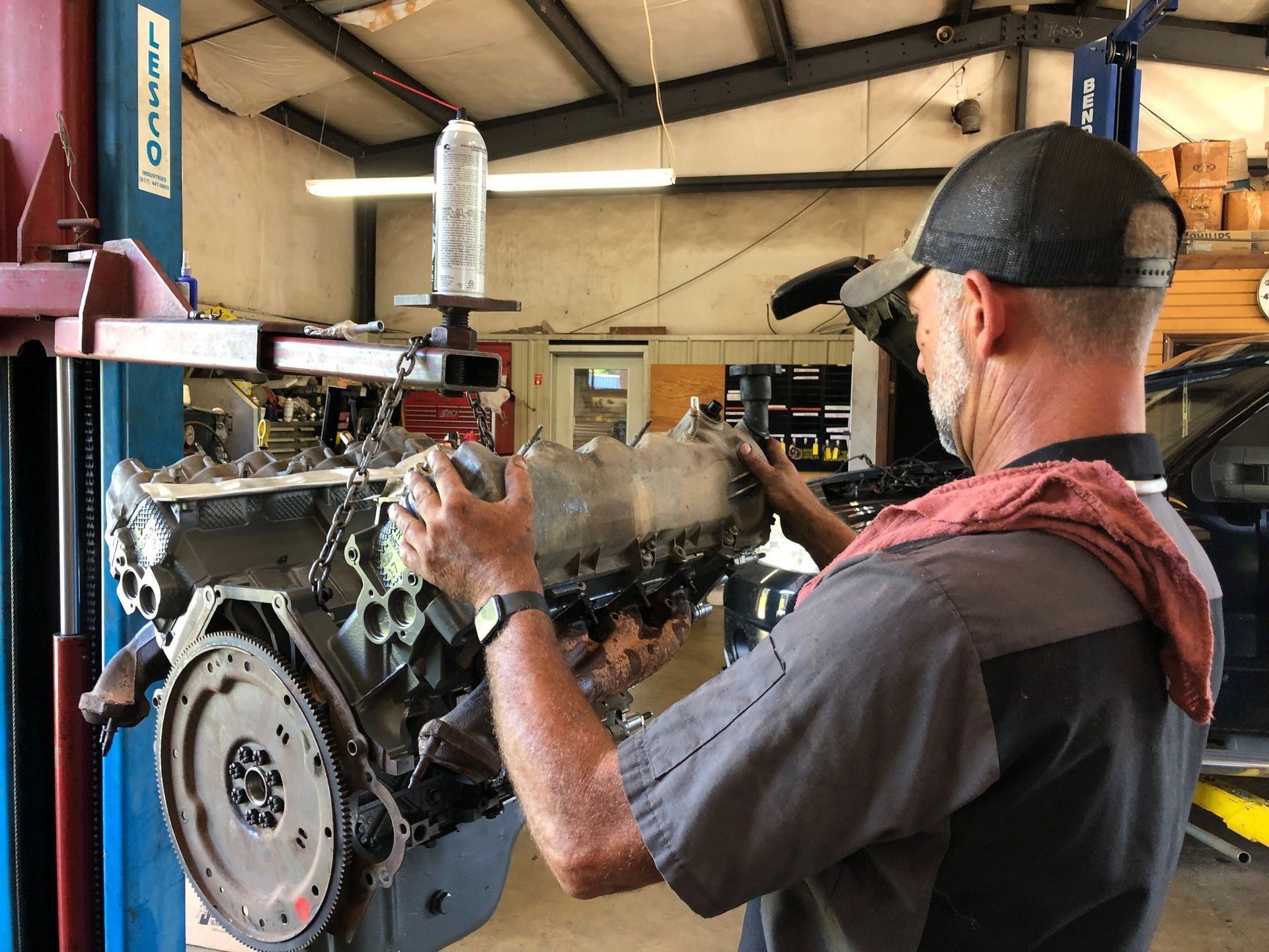 Mechanic working on an engine in a shop, lifting a component.