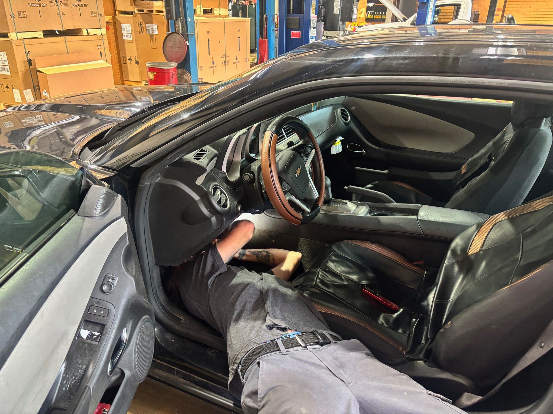 Person reclining in a black sports car with the driver door open in a garage