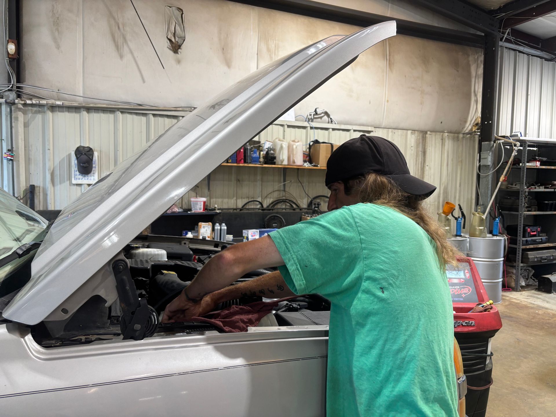 Person working under the hood of a white car in a garage