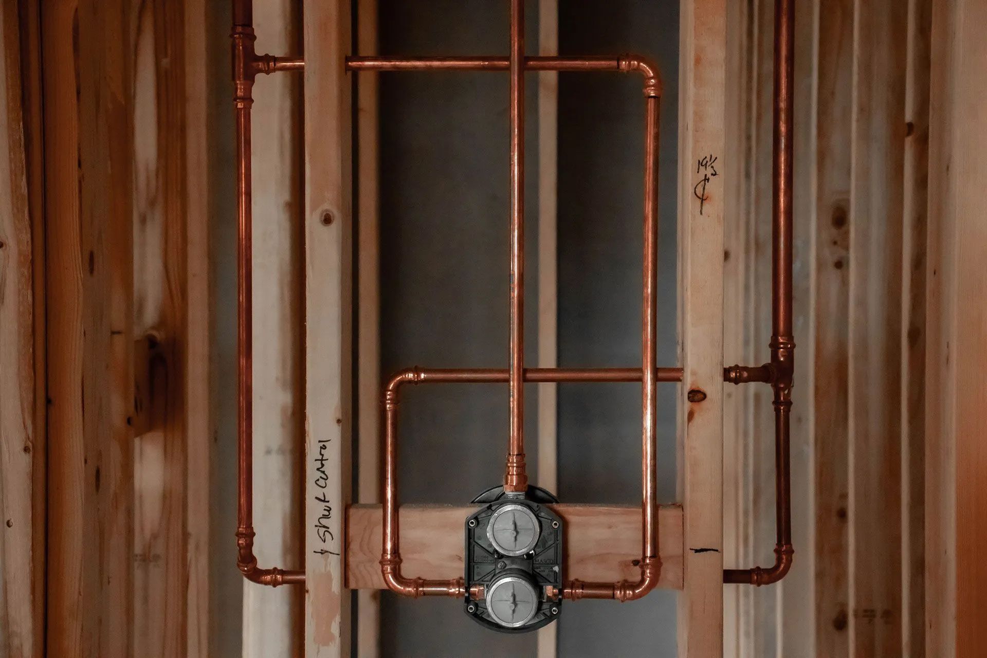Copper pipes installed within a wooden frame, likely for a shower valve.