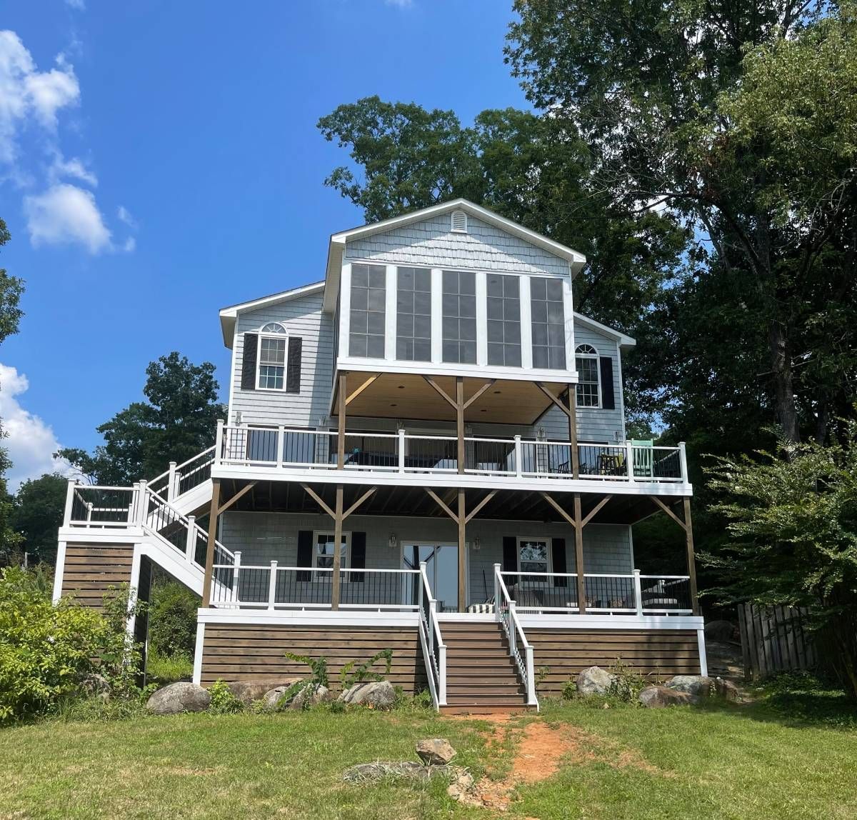A large white house sits on top of a grassy hill