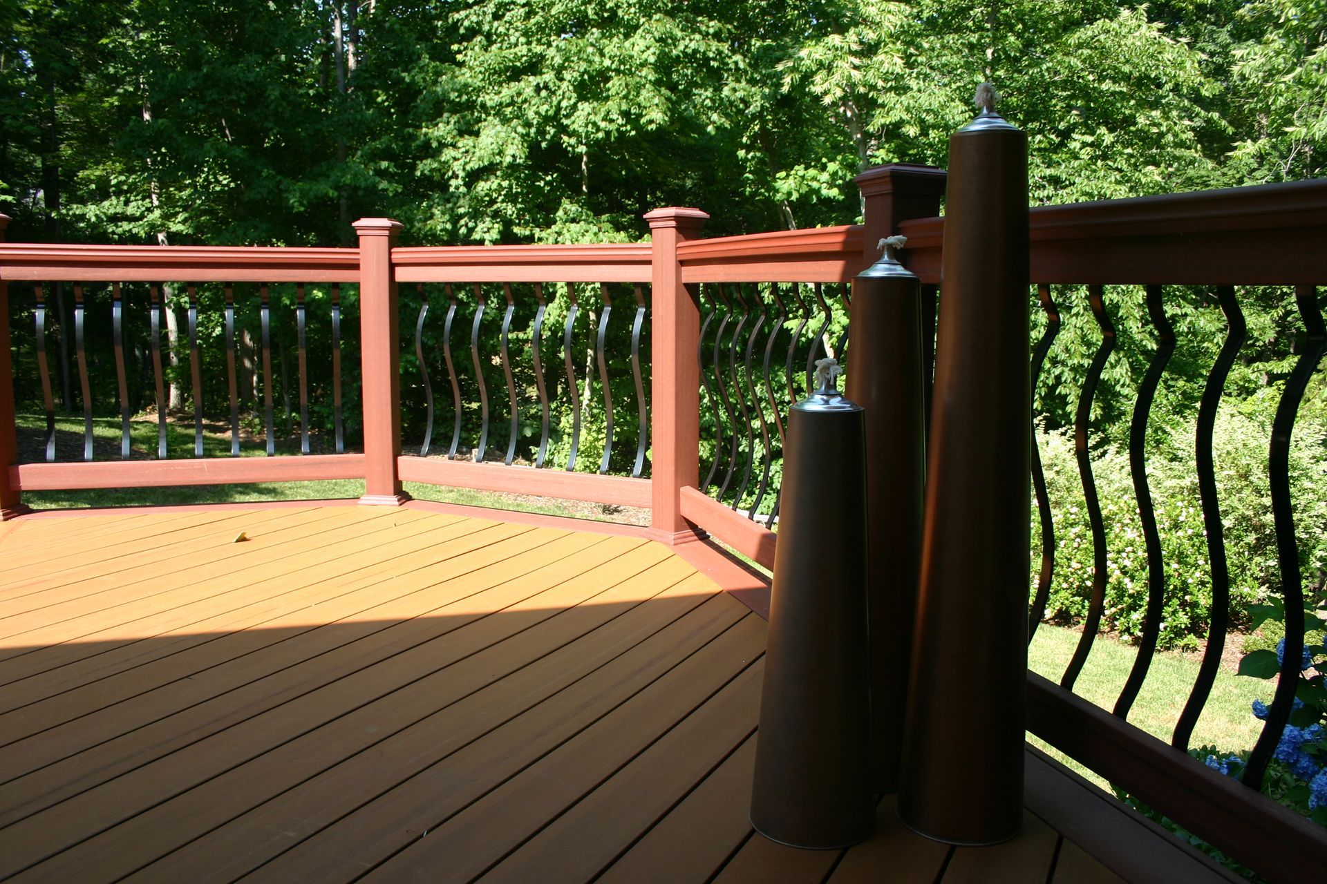 A wooden deck with a metal railing and trees in the background