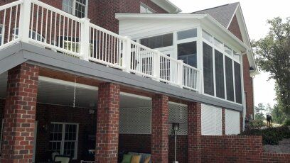 A large brick house with a screened in porch and a white railing.