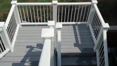 A gray deck with white railing and stairs