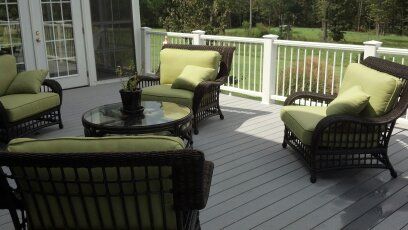 A deck with wicker furniture and a white railing