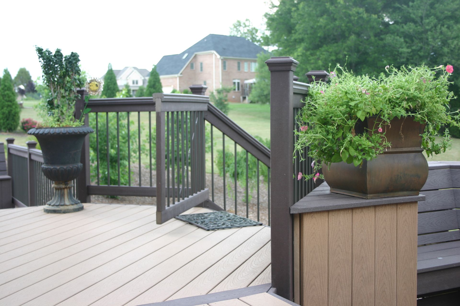 A deck with potted plants and a house in the background