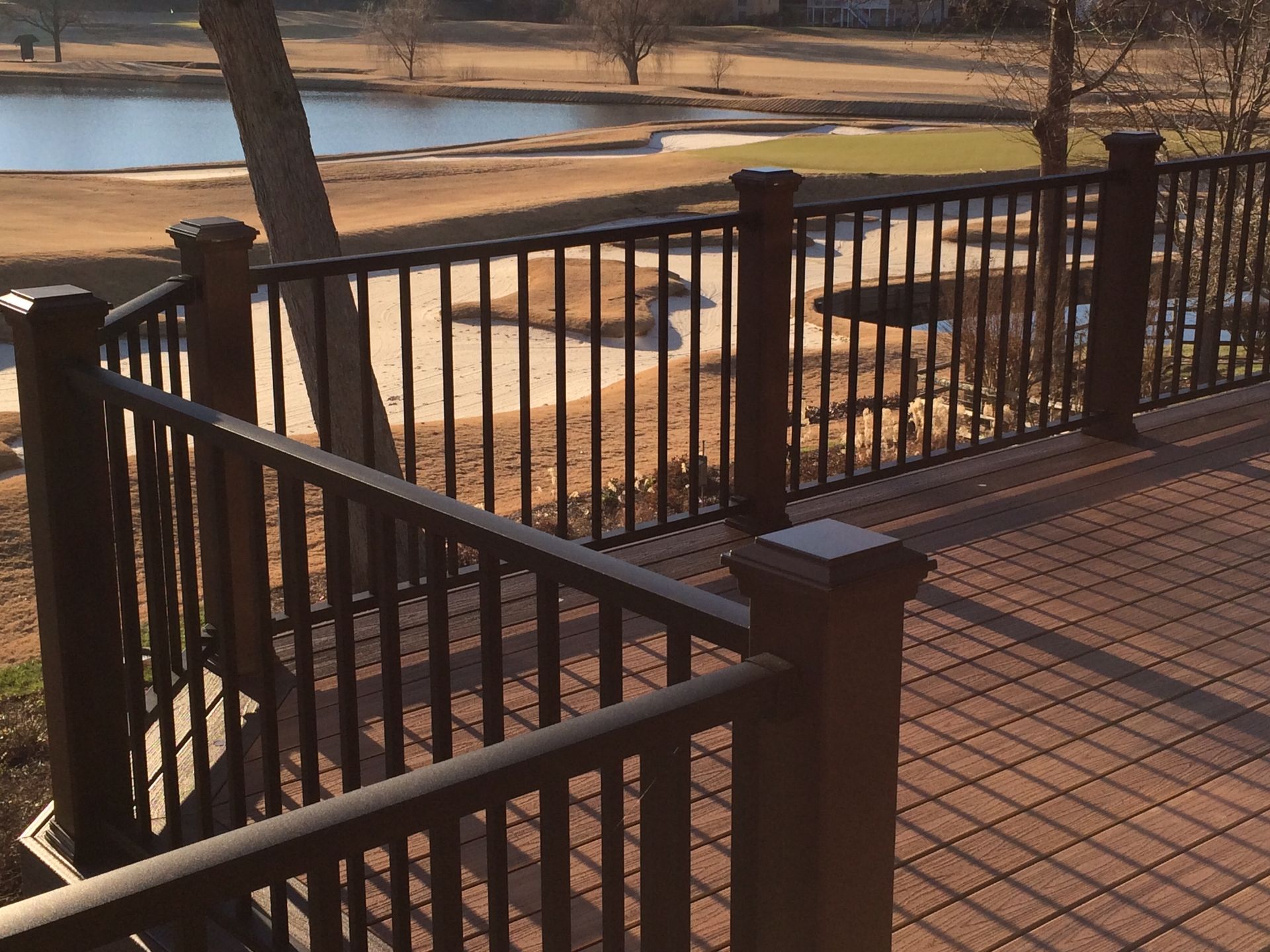 A view of a golf course from a deck with a metal railing