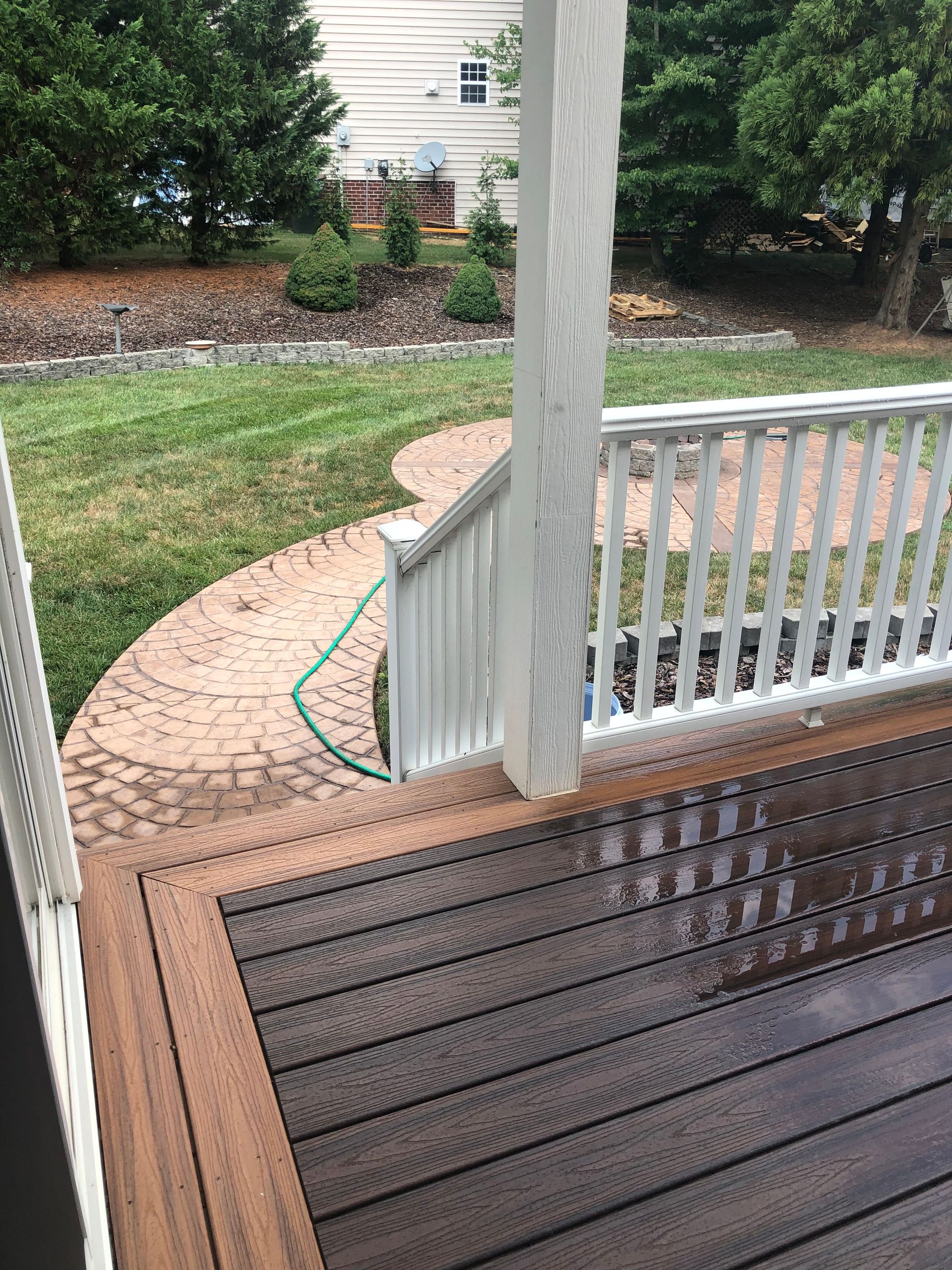 A wooden deck with a white railing and a hose attached to it.